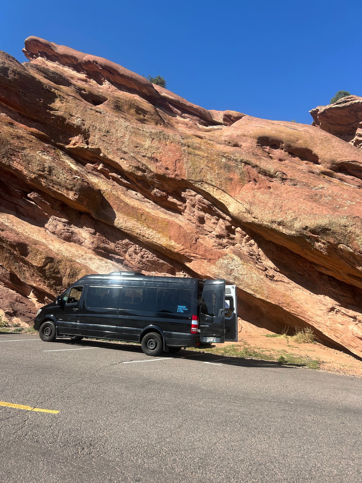 Black van parked on a road with red rock formations in the background