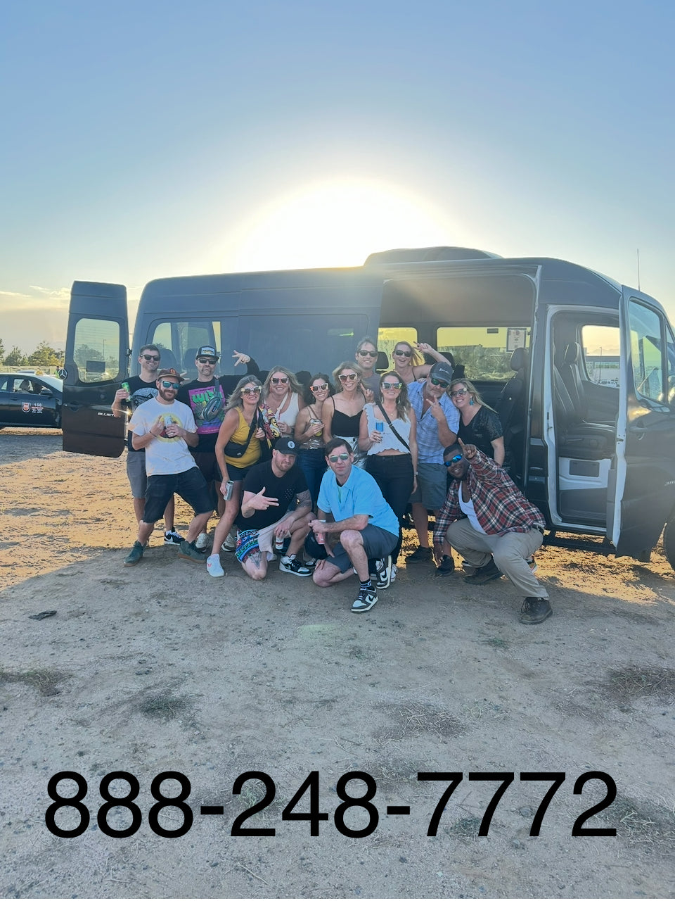 Group of people posing in front of a tour bus with a phone number displayed 888-248-7772 for booking